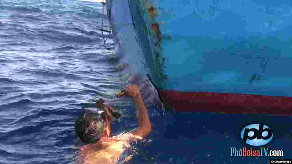 A Vietnamese fisherman repairs his vessel after it was rammed by a Chinese patrol ship that it protecting the waters around a disputed oil rig in the South China Sea, May 18, 2014. (PhoBolsaTV.com)