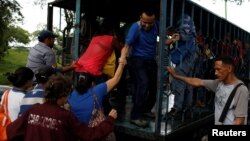 A woman is helped to get on a cargo truck used as public transportation in Valencia, Venezuela, July 11, 2018. 