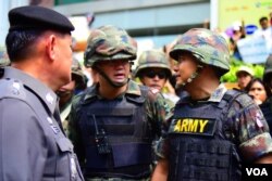 Soldiers and police discuss how to handle a growing crowd of anti-coup protestors in front of a McDonald's restaurant in Bangkok, May 25, 2014. (Steve Herman/VOA)