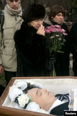 Russia -- Nataliya Magnitskaya (L), mother of Sergei Magnitsky, grieves over her son 's body during his funeral at a cemetery in Moscow, November 20, 2009