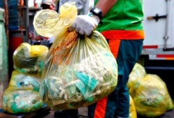 Seorang pekerja memegang kantong sampah medis untuk diangkut ke truk di Jakarta, 12 Agustus 2020. (Foto: Reuters/Ajeng Dinar Ulfiana)