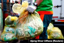 Seorang pekerja memegang kantong sampah medis untuk diangkut ke truk di Jakarta, 12 Agustus 2020. (Foto: Reuters/Ajeng Dinar Ulfiana)