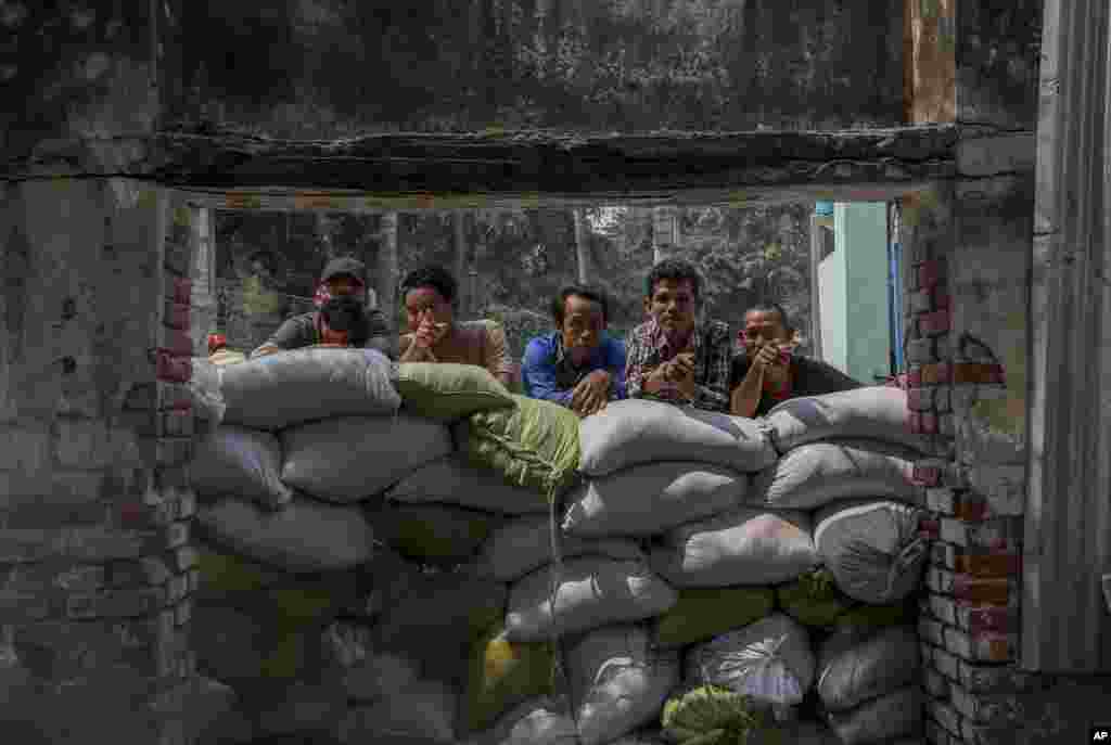 People watch as a convoy of soldiers and policemen arrive with bulldozers to remove makeshift barricades made by anti-coup protesters in Mandalay, Myanmar.