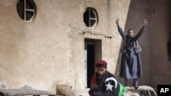 Libyan anti-regime demonstrators gesture at a burnt police station in the eastern city of Tobruk on February 25, 2011.