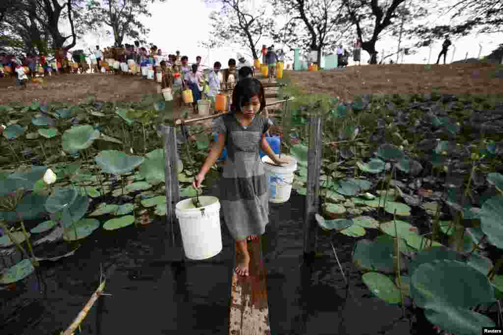 People line up to collect water at Yazarthingyan lake in Dala township, near Rangoon, Burma, since the inland lakes have all dried up in hot summer.