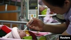 Two-hour old daughter of 17-year old Nakor is fed by a nurse at a hospital in Chiang Mai's Fang district October 2, 2012.