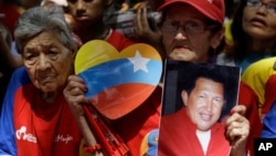 A woman holds a picture of Venezuela's President Hugo Chavez as supporters gather at Simon Bolivar square in Caracas,Venezuela, December 9, 2012.