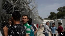 Des migrants et des réfugiés attendent à l'extérieur des bureaux du Service européen d'appui en matière d'asile à l'intérieur du camp de Moria, sur l'île de Lesbos, au nord-est de l'Égée, en Grèce, le 4 mai 2018.