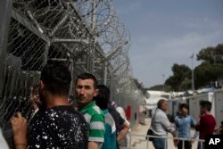 In this May 4, 2018, photo, migrants and refugees wait outside the European Asylum Support Service offices inside the camp of Moria on the northeastern Aegean island of Lesbos, Greece. Migration flows are rising, the camps are severely overcrowded. The asylum process is slow, fueling frustration among migrants and island residents.