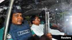 FILE - Mohammad Kamaruzzaman, center, of the Jamaat-e-Islami party sits inside a police van after hearing the verdict of his trial in Dhaka, May 9, 2013. 