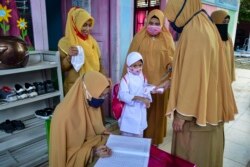 Para guru memeriksa suhu tubuh anak didiknya sebagai tindak pencegahan merebaknya virus Covid-19 di sebuah TK di Banda Aceh, 5 Januari 2021. (Photo by CHAIDEER MAHYUDDIN / AFP)