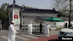 在2020年4月4日清明节期间，北京的医护人员在一个墓园外给驶入汽车驾驶员量体温。