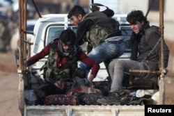 Free Syrian Army fighters ride on a pick-up truck with a fellow fighter, who was injured during an offensive, on the outskirts of the northern Syrian town of al-Bab, Jan. 10, 2017.
