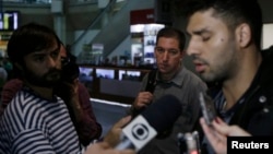 David Miranda (phải) trả lời báo giới sau khi đến sân bay quốc tế Rio de Janeiro, Brazil, hôm Chủ nhật. Ðứng giữa là nhà báo Mỹ Glenn Greenwald.