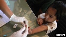 ကရင်ကလေးငယ်တစ်ဦး ငှက်ဖျားရောဂါပိုး ရှိမရှိ စစ်ဆေးနေစဉ်။
