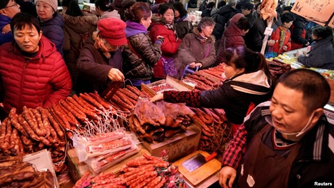 置辦年貨的北京市民在超市的臘肉臘腸攤位前選購。（2020年1月16日）