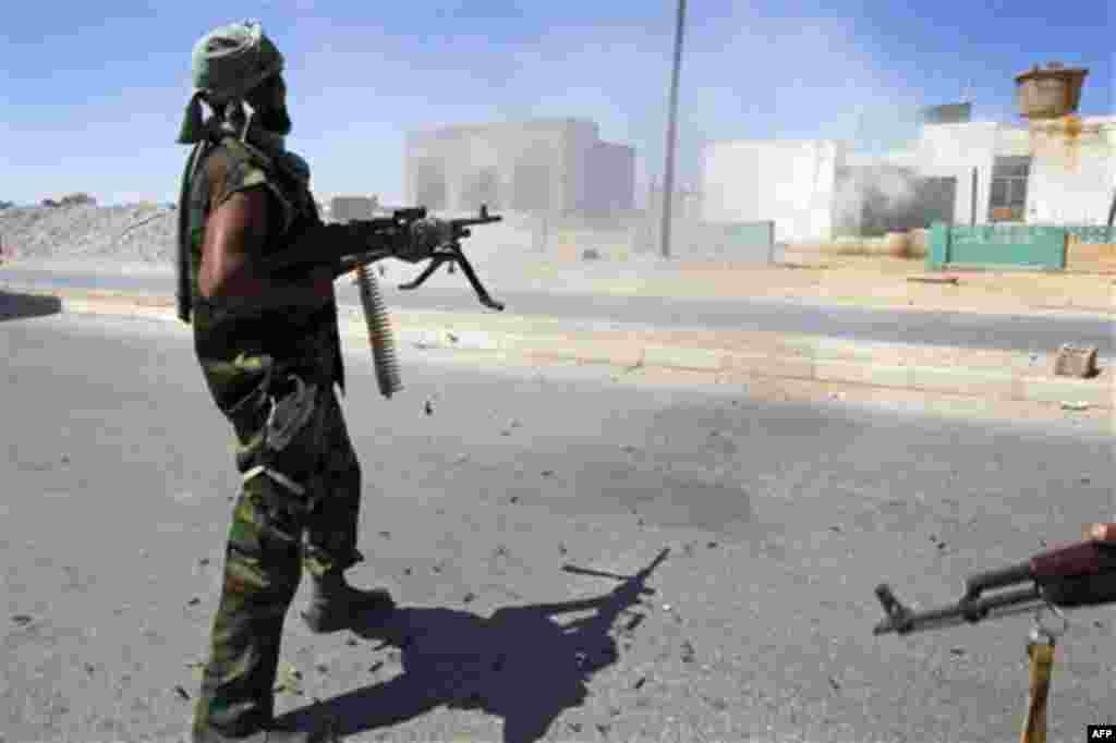 Libya fighter fire his machine gun at a Moammar Gadhafi political office next to a police station as they take control of Moammar Gadhafi loyalists villages in the desert some 730 kms south of Tripoli, at Mahruga, 50 kms north of the southern city of Sebb