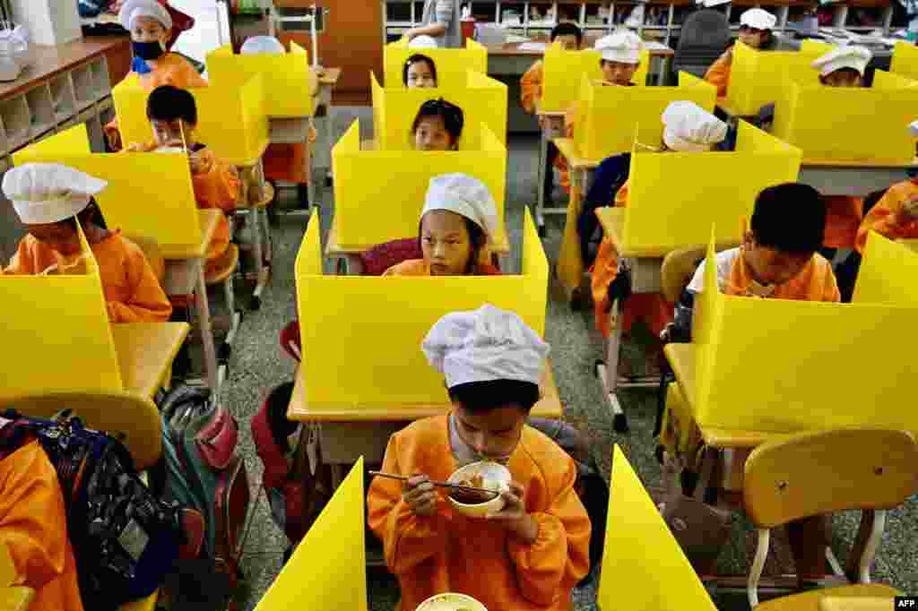 Students eat their lunch on desks with plastic separations as a preventive measure to stop the spread of the COVID-19, at Dajia Elementary School in Taipei, Taiwan.