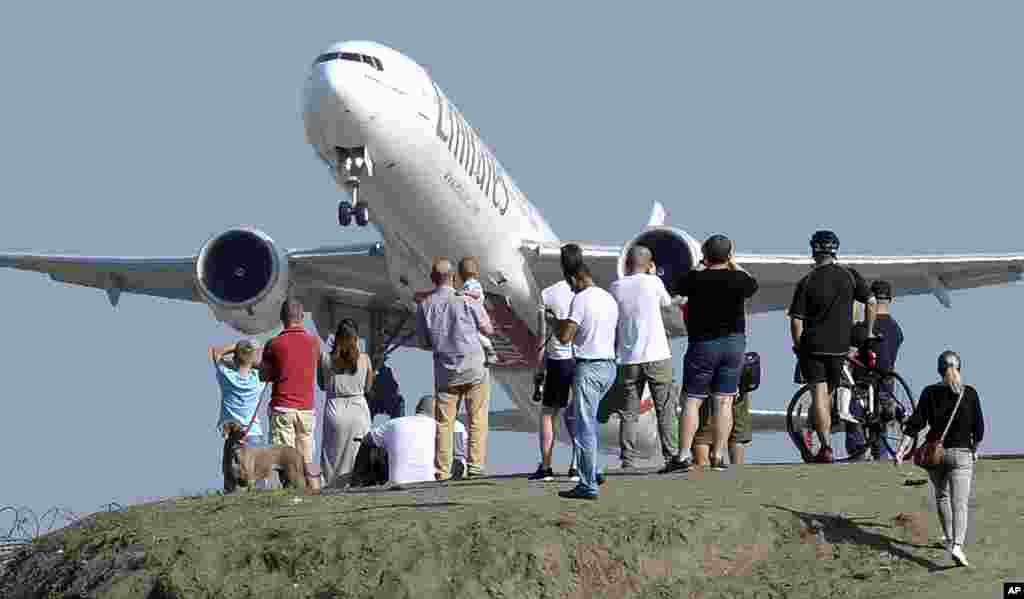 People gather on a hill near the Chopin Airport to watch aeroplanes taking off in Warsaw, Poland.