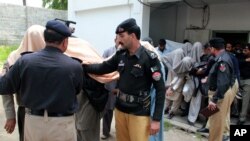 Pakistani police officers escort members of a local tribal council, with their faces covered outside a court in Abbottabad, Pakistan, May 5, 2016. 