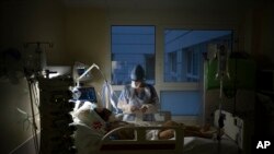 A nurse watches over a COVID-19 patient on a ventilator in the COVID-19 intensive care unit at the la Timone hospital in Marseille, southern France, Dec. 31, 2021.