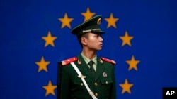 FILE - A Chinese policeman stands in front of the European Union flag outside the office of the European Union delegation to China in Beijing, Oct. 28, 2011. 