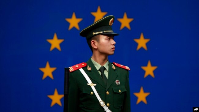 一名中国警察站在欧盟驻华代表团办公室外的欧盟旗帜前。