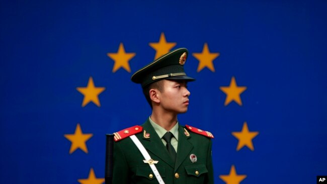 一名中国警察站在欧盟驻华代表团办公室外的欧盟旗帜前。