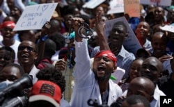 FILE - A doctor holds his stethoscope in the air as he and other medical staff protest the detention of their union leaders, outside an appeal court in Nairobi, Kenya, Feb. 15, 2017.