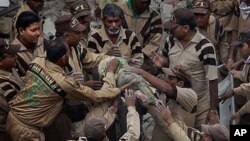 Rescue workers pull out the body of a child from the remains of a four-story apartment building that collapsed in New Delhi, India, 16 Nov 2010