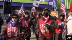 In this grab taken from TV, protesters hold flags and play instruments outside the Olympic Stadium in Pyeongchang, South Korea, Feb. 9, 2018.