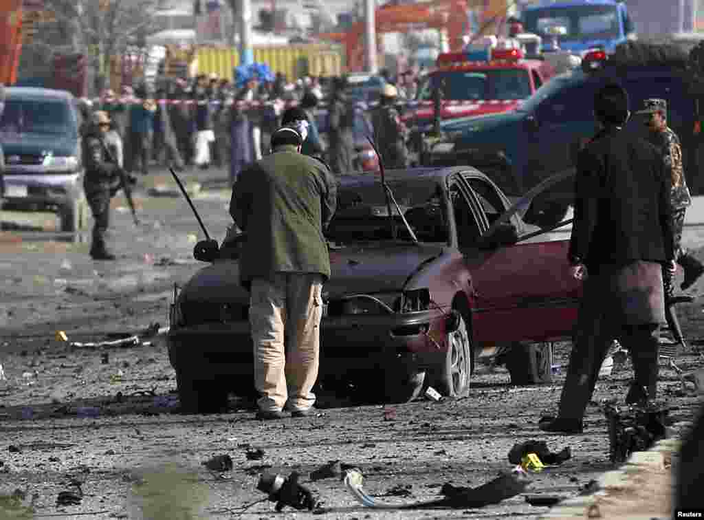 Afghan security forces inspect the site of a suicide attack on a British embassy vehicle in Kabul, Nov. 27, 2014.