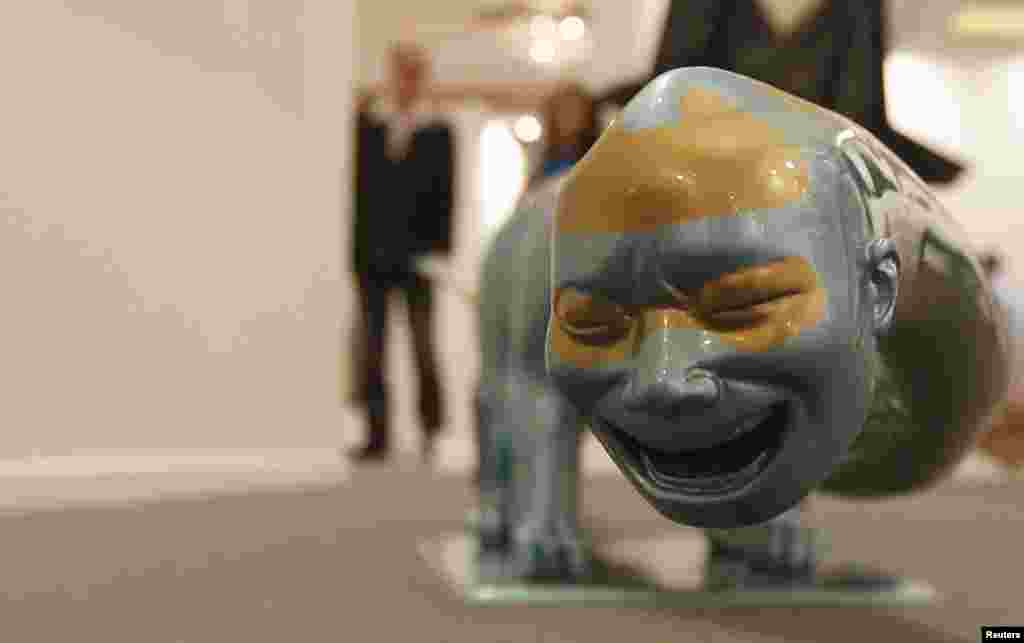 在阿聯酋舉行的迪拜藝術展媒體預展中，參觀者走過中國藝術家岳敏君的雕塑作品。