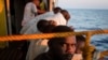 Les migrants se reposent sur le pont d'un bateau, après avoir été sauvés au large des côtes libyennes le 2 août 2018.
