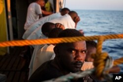 FILE - Migrants rest on the deck of the Open Arms boat, after being rescued off the coast of Libya in the early hours of the nigh of Thursday, Aug. 2, 2018.