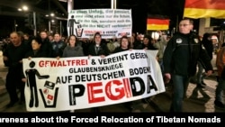 Manifestantes con un poster que lee "Sin violencia y unidos contra las guerras religiosas en tierra alemana -PEGIDA", durante una protesta en Dresden, Alemania.