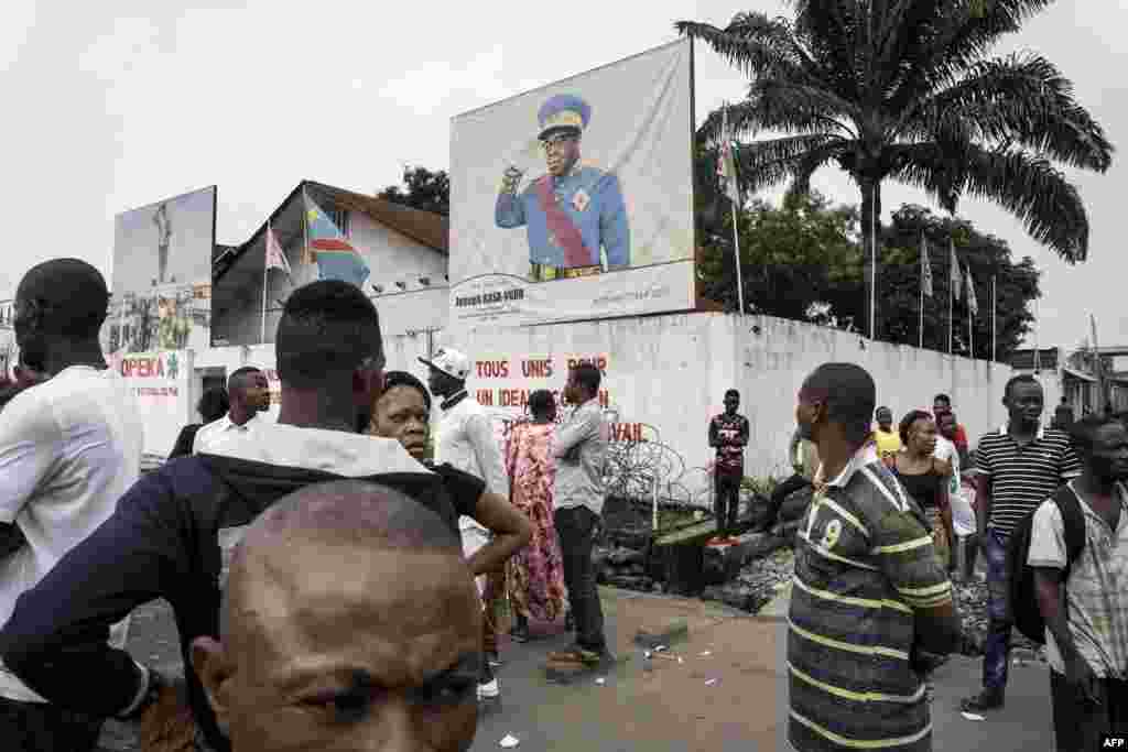Des badauds regardent des manifestants lors d'une marche contre Kabila qui appelle à sa démission, le 21 janvier 2018 à Kinshasa.