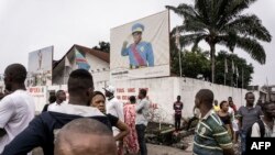 Des badauds regardent des manifestants lors d'une marche contre Kabila qui appelle à sa démission, le 21 janvier 2018 à Kinshasa.