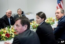 U.S. Secretary of State Rex Tillerson, left, Russia's Foreign Minister Sergei Lavrov, right, and others wait for the start of a meeting at the World Conference Center, in Bonn, Germany, Feb. 16, 2017, as part of a broader G-20 meeting.