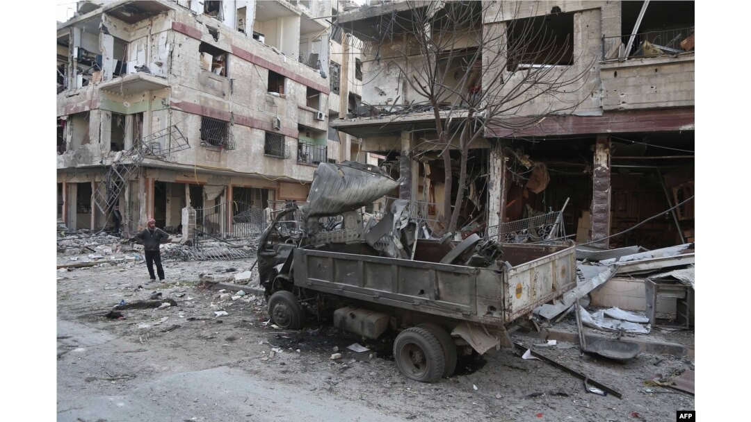 FILE - A Syrian man pauses near destruction following a reported regime air strike in the rebel-held town of Hamouria, in the besieged Eastern Ghouta region on the outskirts of the capital Damascus, Feb. 21, 2018.