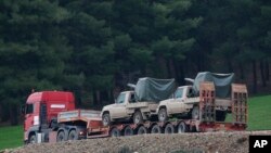 Sebuah truk, bagian dari sebuah konvoi, membawa truk pickup militer dengan senapan mesin yang terpasang terlihat di pinggiran desa Sugedigi, Turki, 21 Januari 2018.