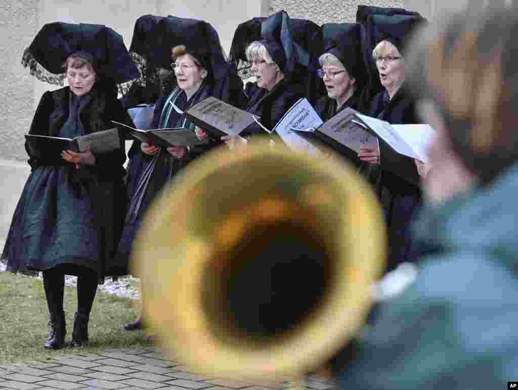 Women in traditional costumes sing in front of the church in Burg, eastern Germany, Easter Sunday.