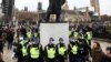 Des policiers se tiennent autour d'une statue lors d'une manifestation contre le confinement à Londres, en Grande-Bretagne, le 20 mars 2021.