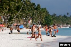 Tourists walk on White Beach on the resort island of Boracay, south of Manila, Feb. 2, 2008.