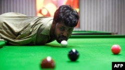 In this picture taken on September 28, 2020, Muhammad Ikram plays a shot with his chin at a local snooker club in Samundri. 