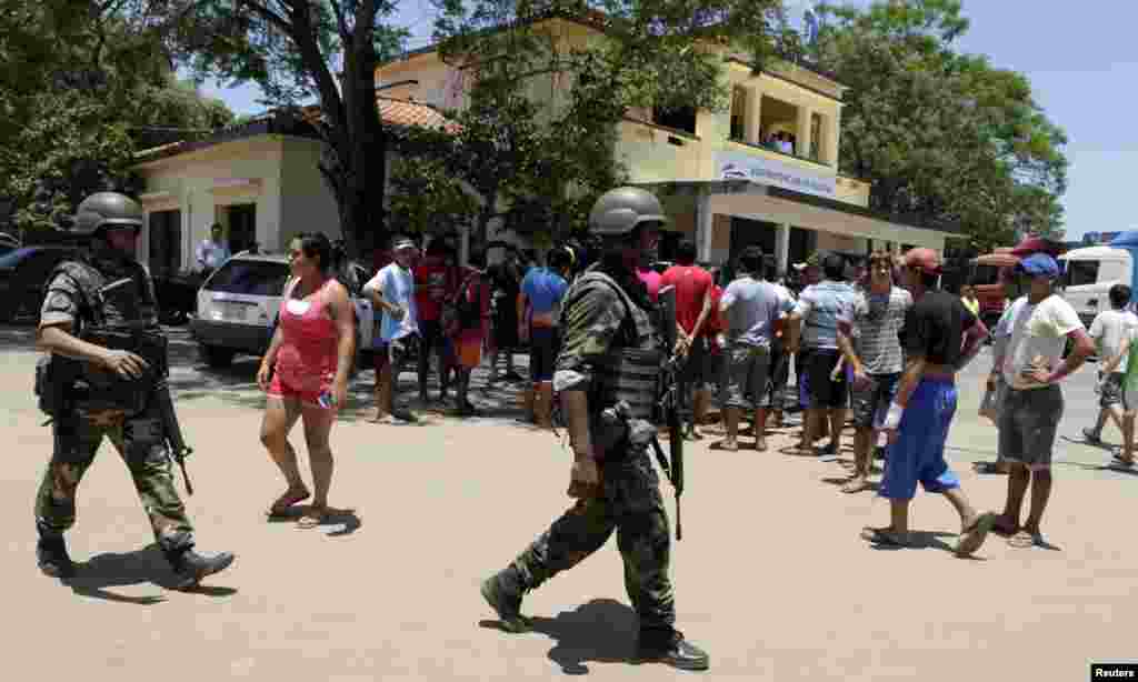 Soldiers patrol near protesters at the customs administration building in the port of Ita Enramada, which is located opposite from the Argentine city of Clorinda, on the outskirts of Asuncion, November 27, 2013.