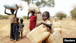 FILE - Children carry belongings as they go to a refugee camp in South Sudan, May 2, 2012. The United Nations refugee agency reports that renewed violence has trapped more than 100,000 residents and refugees in Yei, which now is surrounded by government forces.