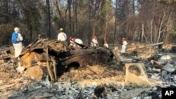 Volunteer members of an El Dorado County search and rescue team search the ruins of a home and vehicle, looking for human remains, in Paradise, Calif., Nov. 18, 2018, following a Northern California wildfire.