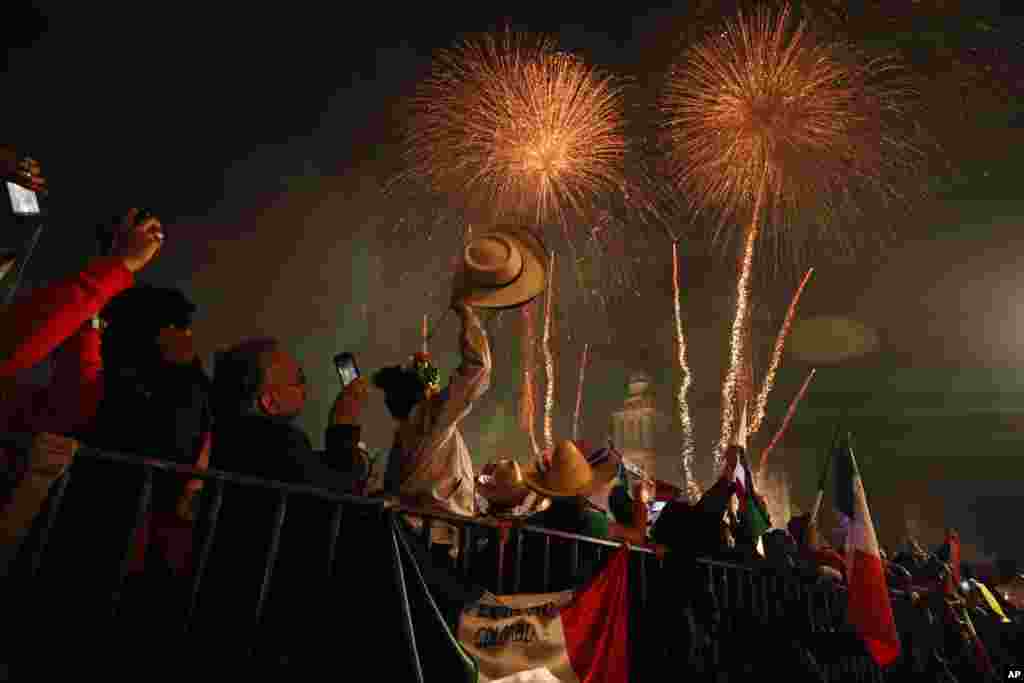 Revelers celebrate as fireworks explode over the Metropolitan Cathedral after President Andres Manuel Lopez Obrador gave the annual independence shout from the balcony of the National Palace to kick off Independence Day celebrations in Mexico City, Sept. 15, 2019.