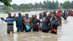 Foto ilustrasi menjukkan sejumlah warga menyeberang jalan yang tergenang banjir di Dar es Salaam, Tanzania, pada 21 Desember 2011. (Foto: AP)